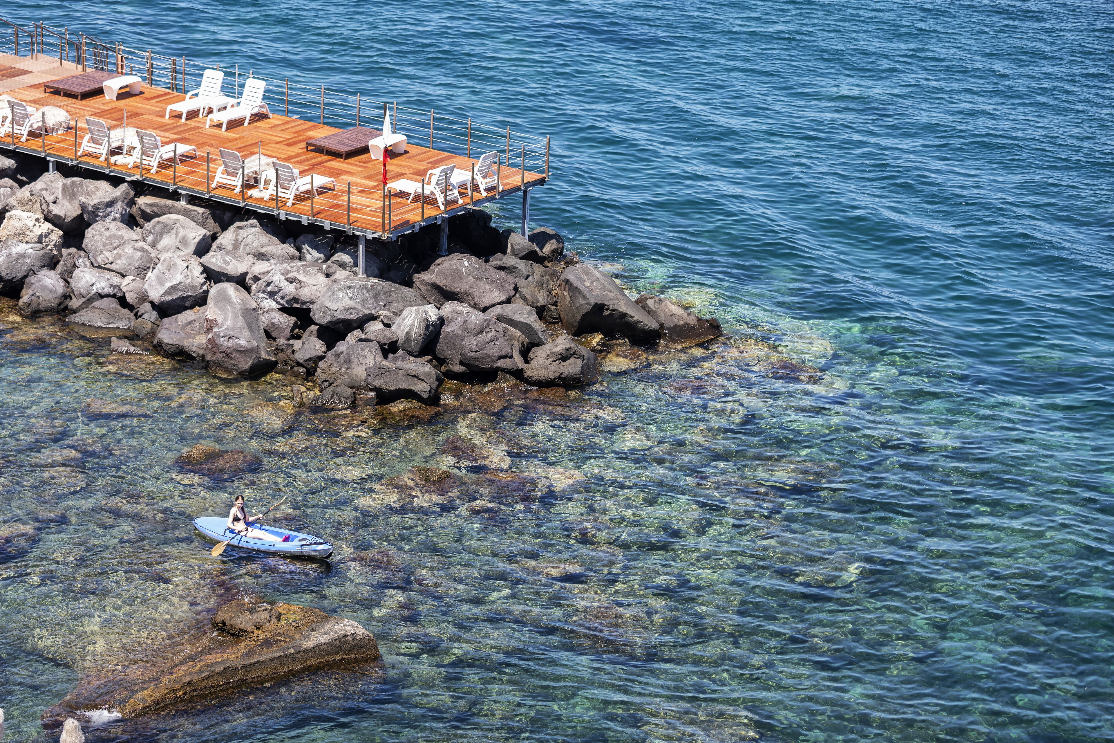 A pier with lounge chairs and a kayak in the water.