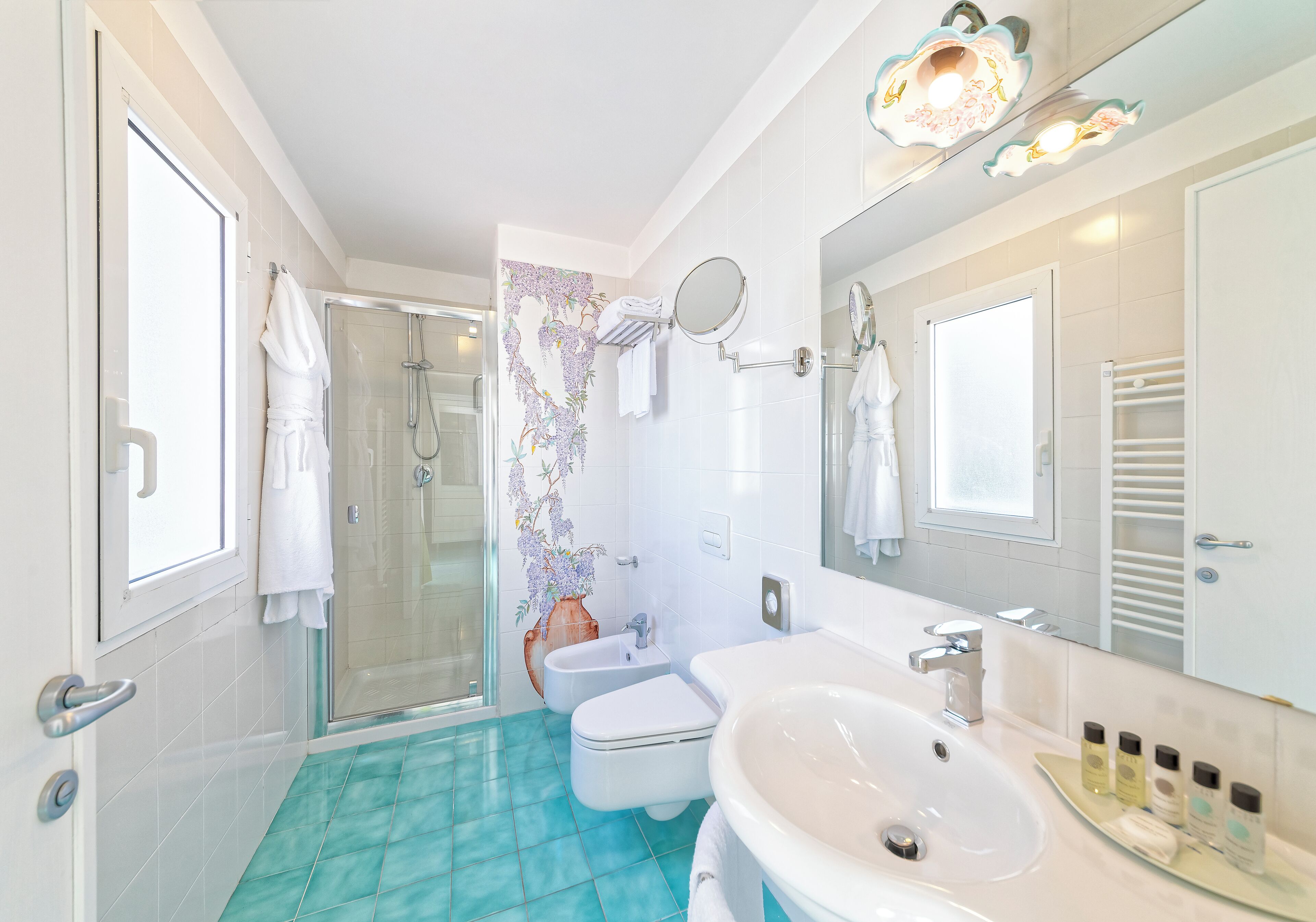 Un baño con cabina de ducha de vidrio, un lavabo blanco y un espejo encima.