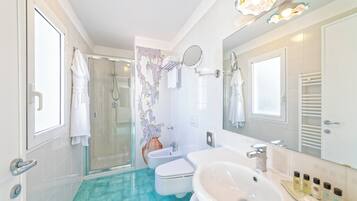 Un baño con cabina de ducha de vidrio, un lavabo blanco y un espejo encima.
