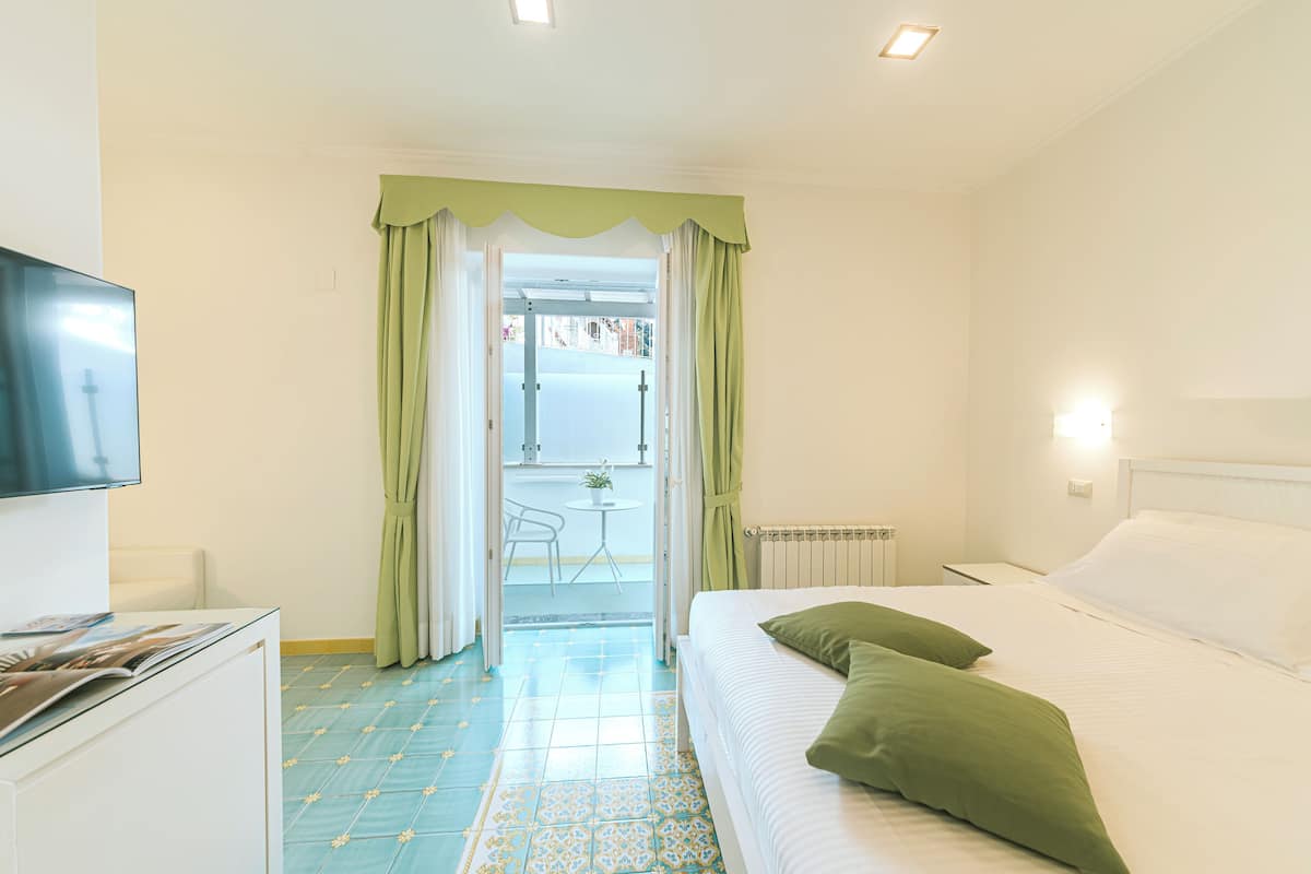 Ein Hotelzimmer mit Bett, Fernseher, Schreibtisch und Blick auf den Balkon.