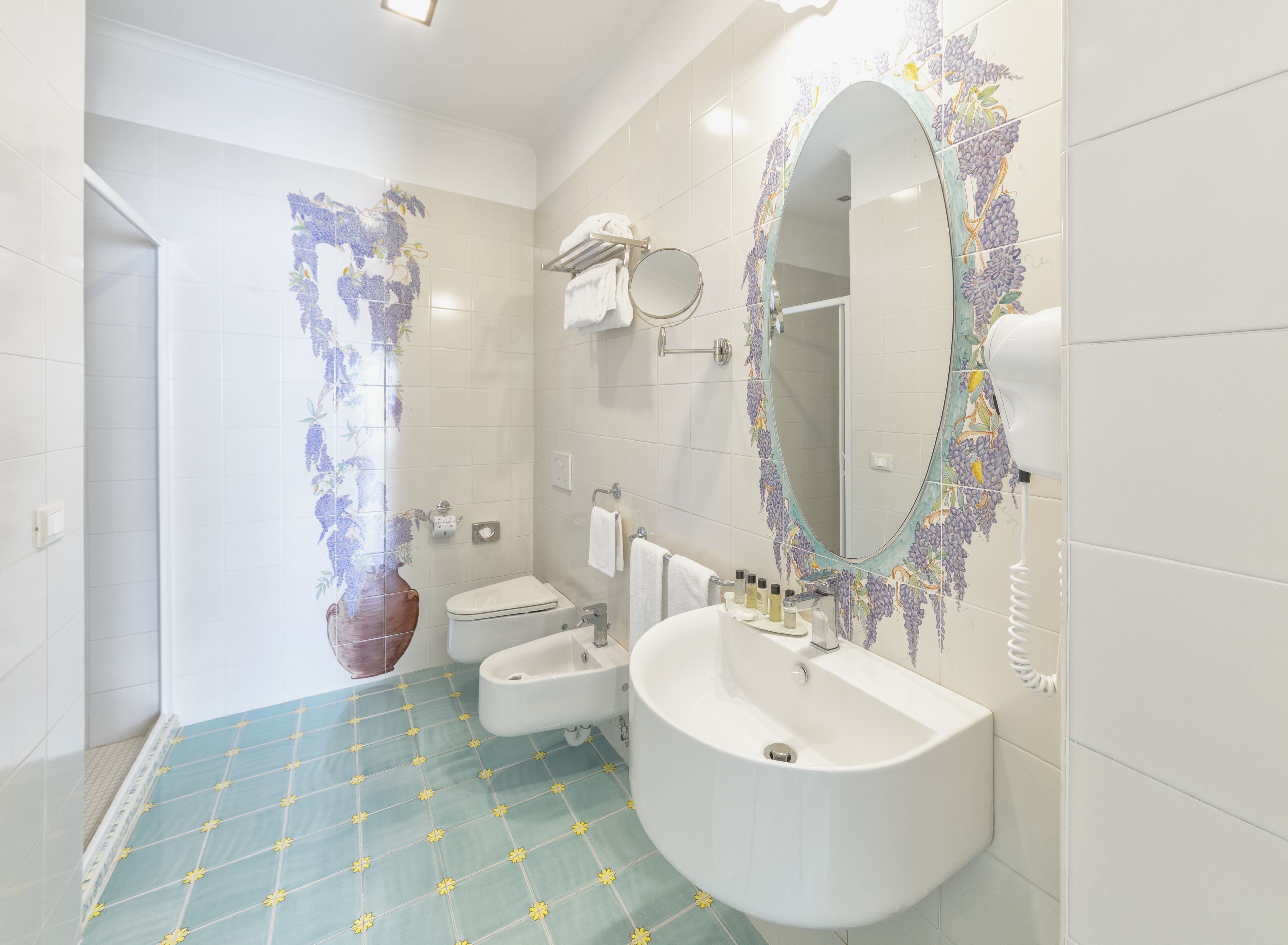 Ein Badezimmer mit einem weißen Waschbecken, einer Toilette, einem Bidet und einem Spiegel mit Zierrahmen.