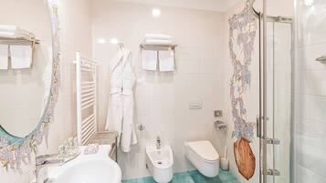Un baño con lavamanos, bidé, inodoro y cabina de ducha de vidrio.