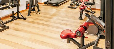 A gym with exercise equipment, a treadmill, and a mirror.
