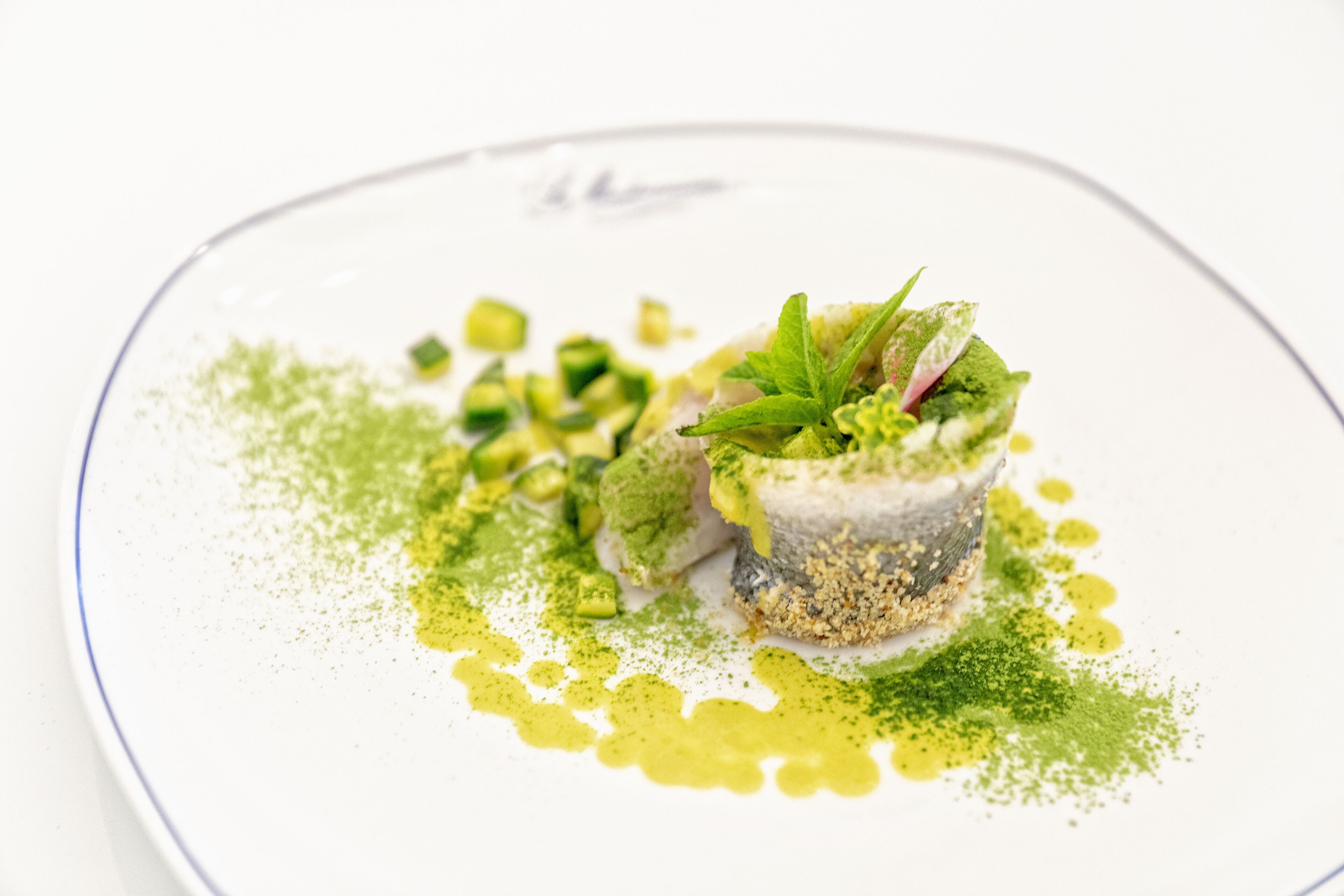 A dish with green elements and a white plate.