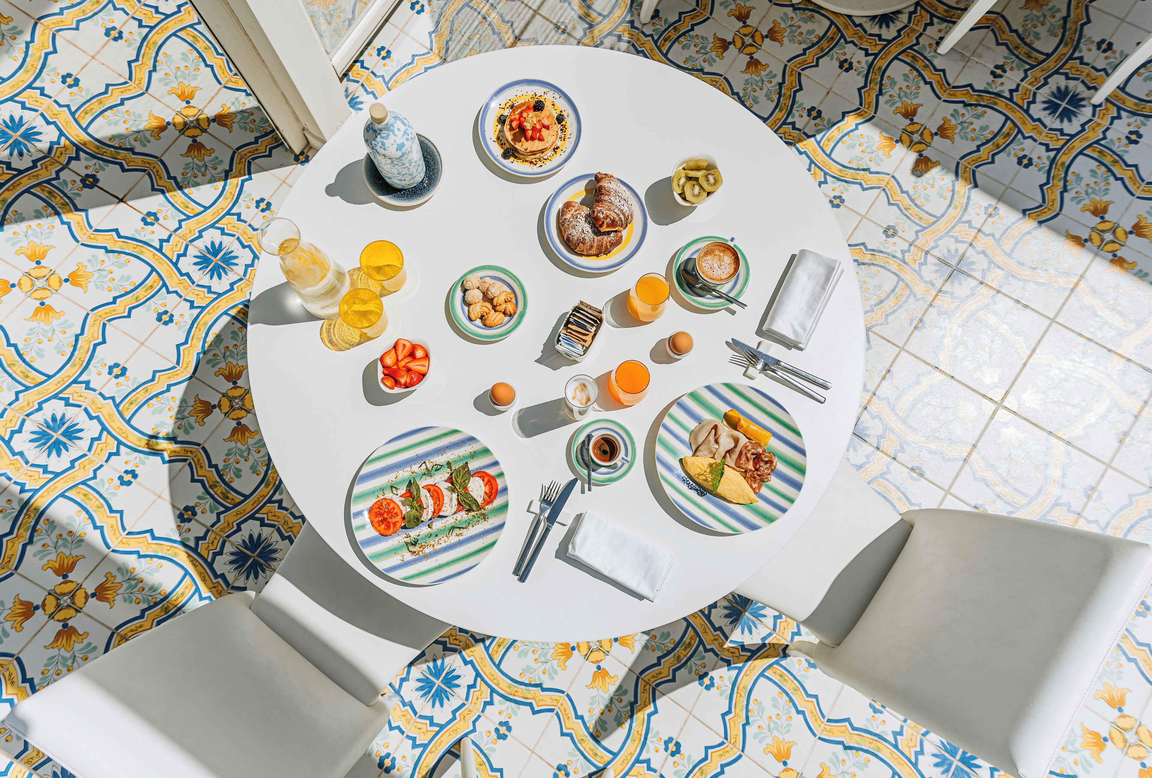 Una mesa redonda con platos de comida, una taza de café y un vaso de jugo de naranja.