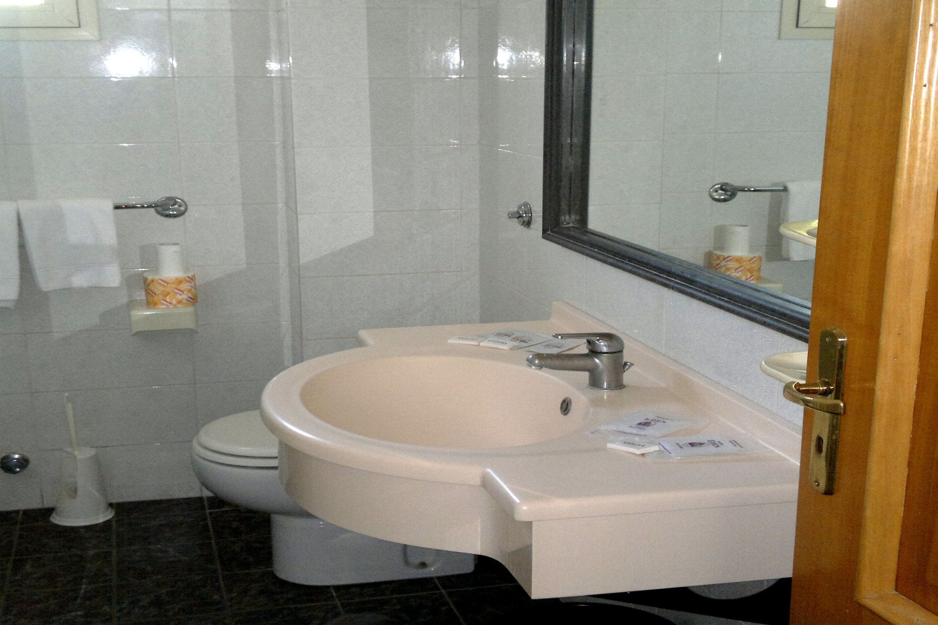 Un baño con inodoro, lavamanos y espejo.