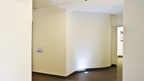 A hallway with a curved wall, a light fixture, and a door at the end. - Hotel Eden (Sorrento)