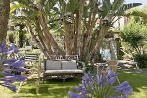 Un jardín con un sofá de mimbre, sillas y una valla de madera.