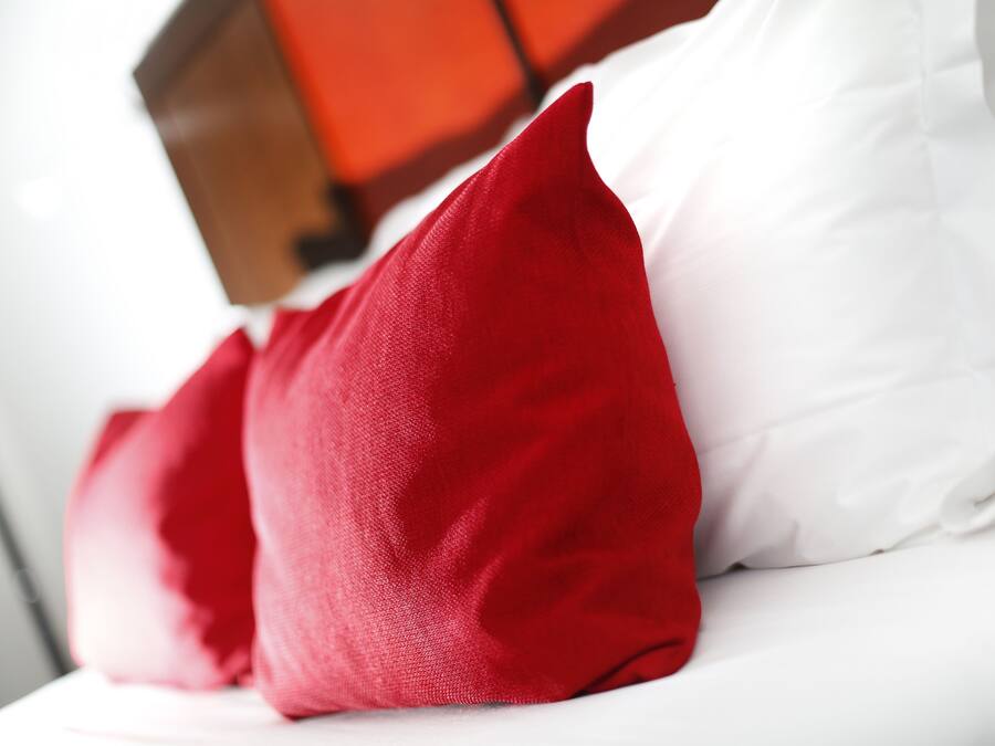 A close-up of a bed with white and red pillows.