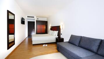 Une chambre d’hôtel moderne équipée d’un lit, d’un canapé, d’une télévision et d’un miroir.