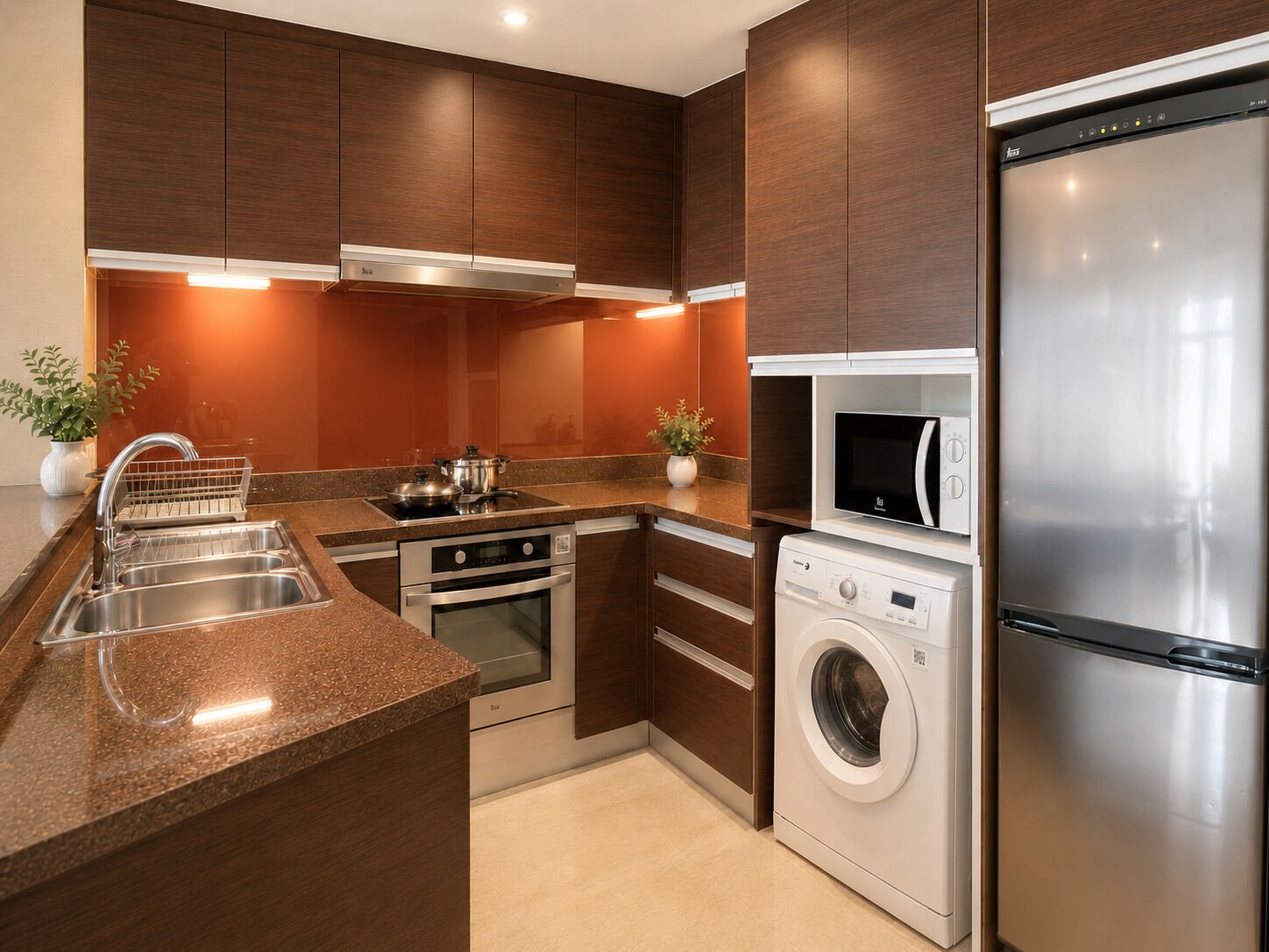 A modern kitchen with stainless steel appliances, a built-in oven, microwave, and washing machine, and wooden cabinetry.