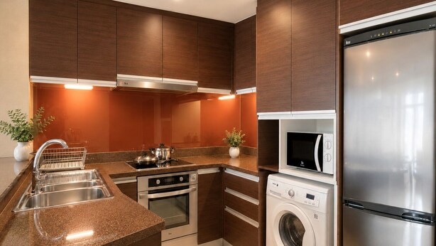 Eine moderne Küche mit Edelstahlgeräten, einem Backofen, einer Mikrowelle und einer Waschmaschine, sowie Holzschränken.
