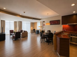 Hotelkamer met een eetgedeelte, een zithoek, een bureau en een kitchenette.