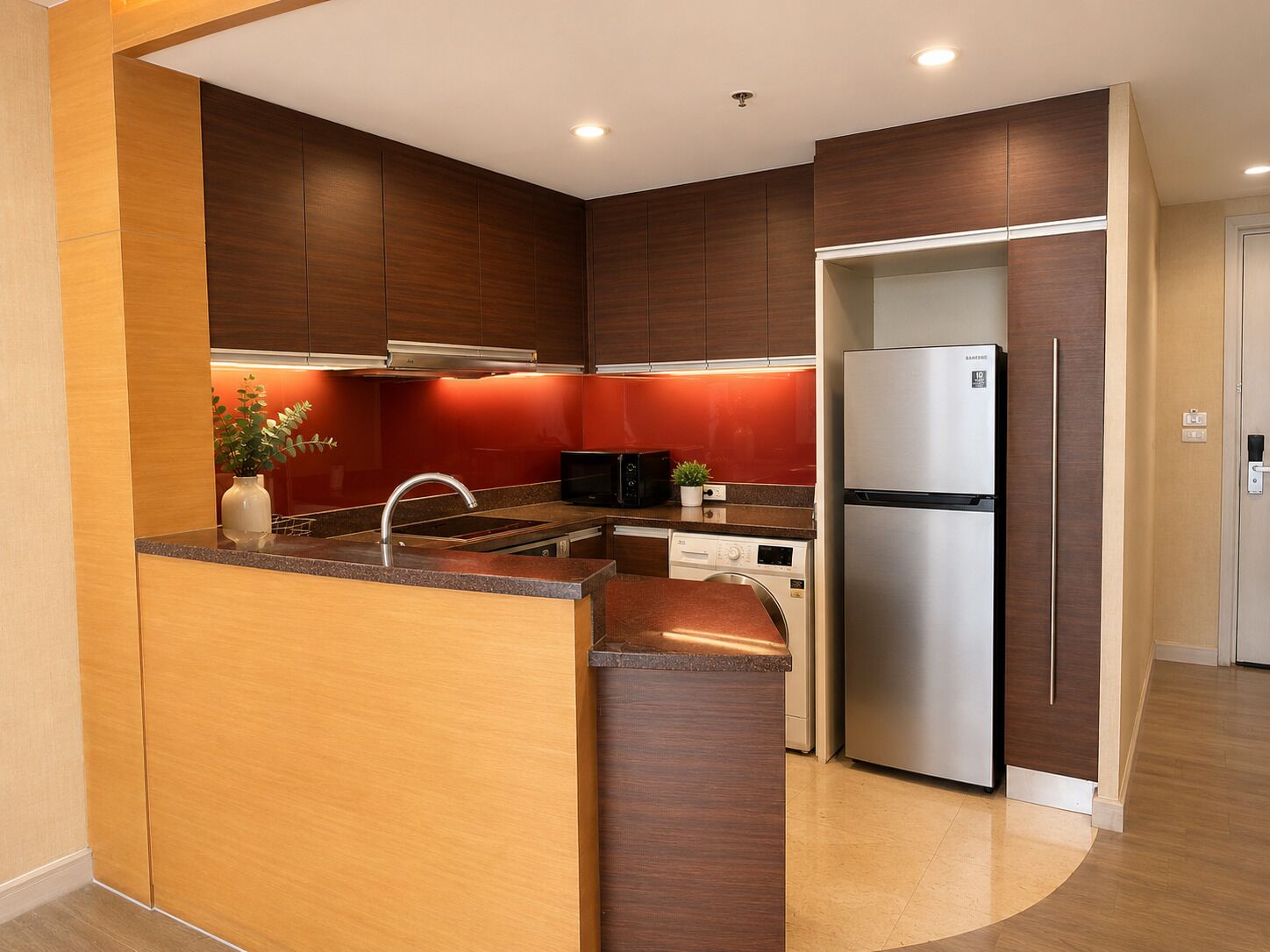 A modern kitchen with a built-in island, stainless steel appliances, and a red backsplash.