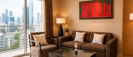 A modern hotel room with a city view, a sofa, a chair, a table, and a lamp.