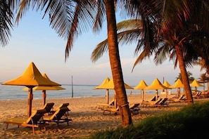 Une plage avec des transats et des parasols jaunes.
