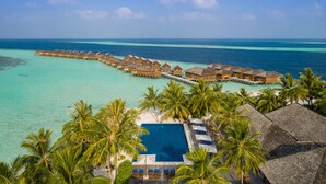 An overwater bungalows with a pool and palm trees.