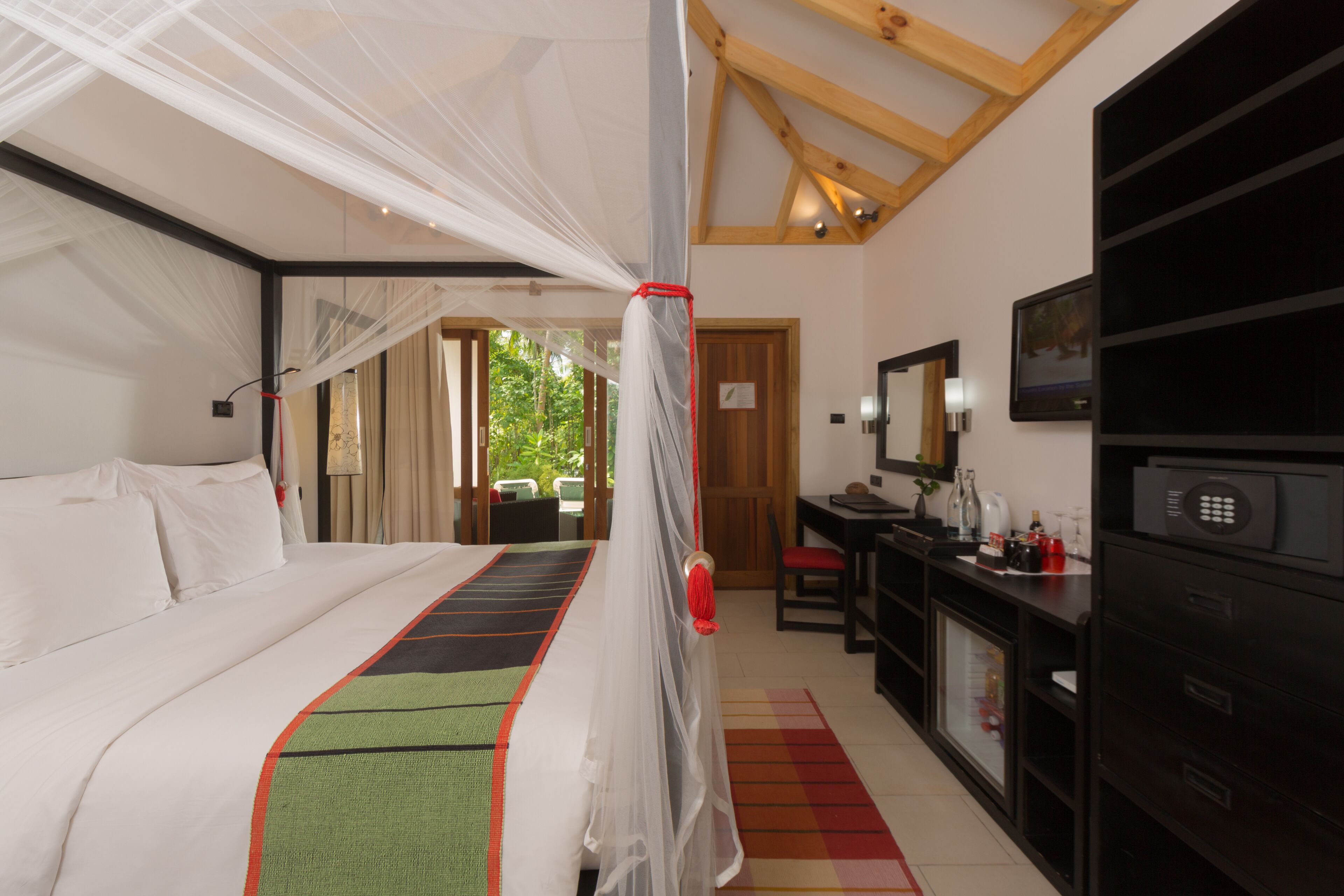 Ein Hotelzimmer mit Bett, Schreibtisch, Fernseher und Minibar.