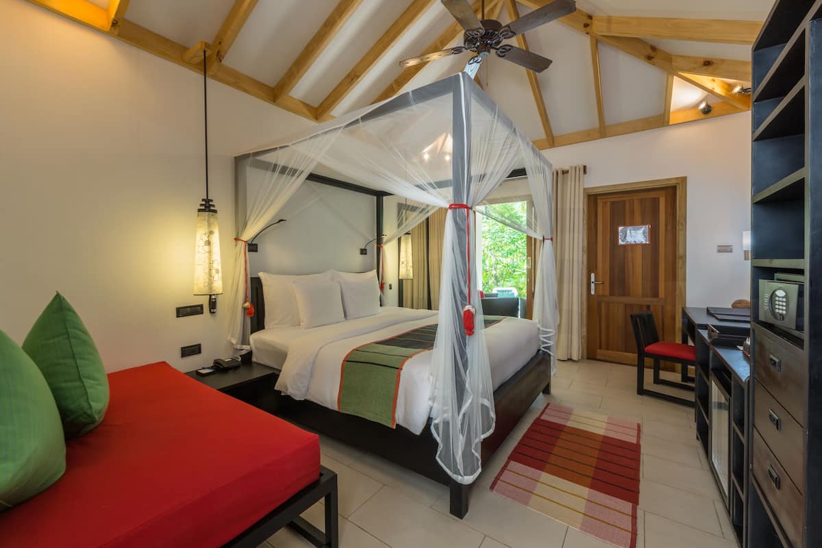 A bedroom with a canopy bed, a desk, a chair, and a wardrobe.