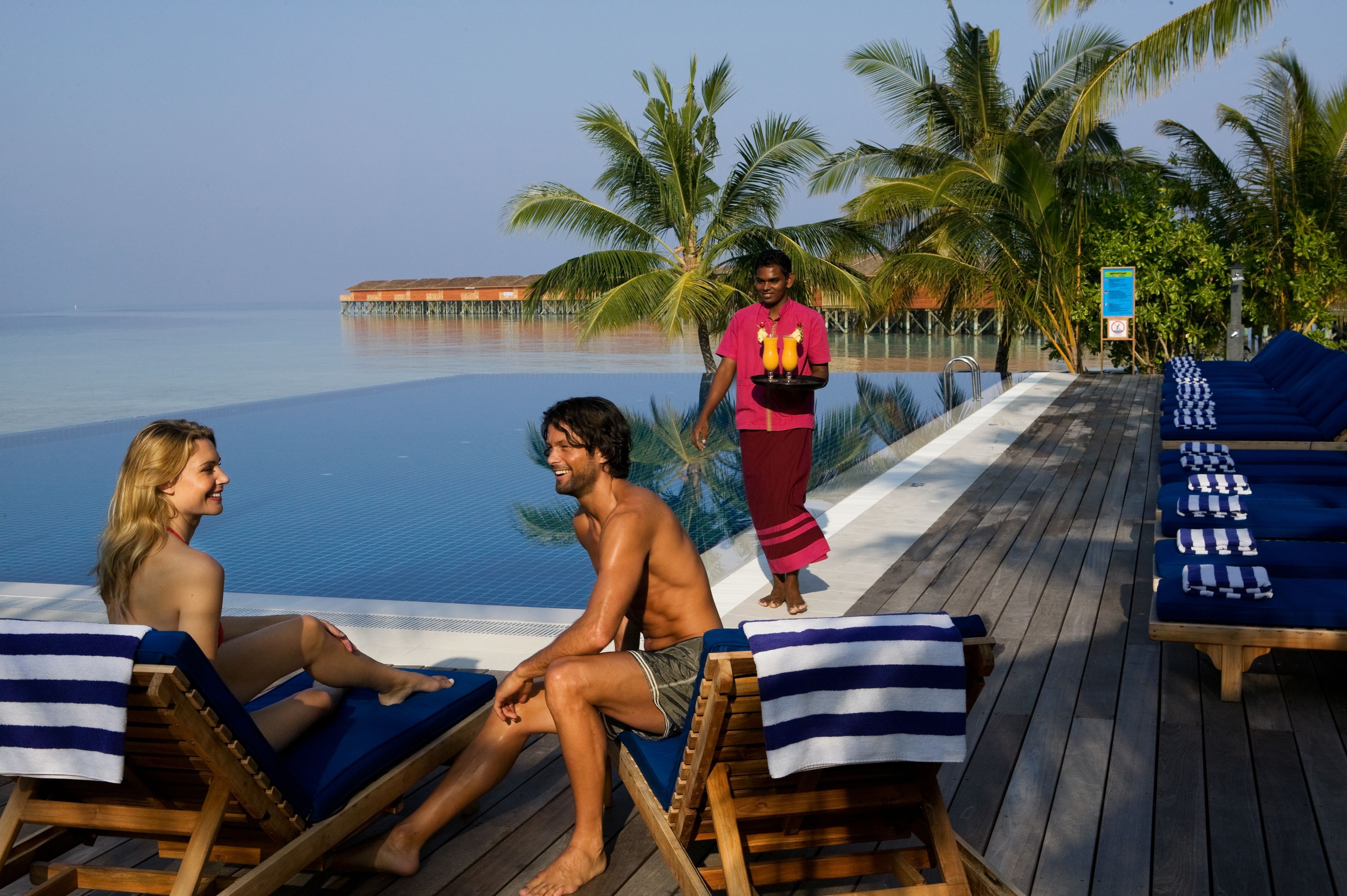 Un espace aménagé au bord de la piscine, avec des chaises longues et une personne qui sert des boissons.