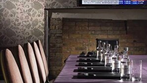 A conference room with a long table, chairs, and a television displaying a graph. - The Boleyn Hotel (Staines)