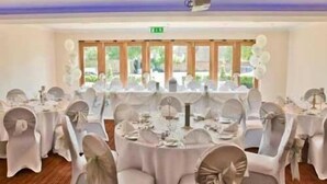 A banquet hall with round tables, white tablecloths, and grey chairs. - The Boleyn Hotel (Staines)