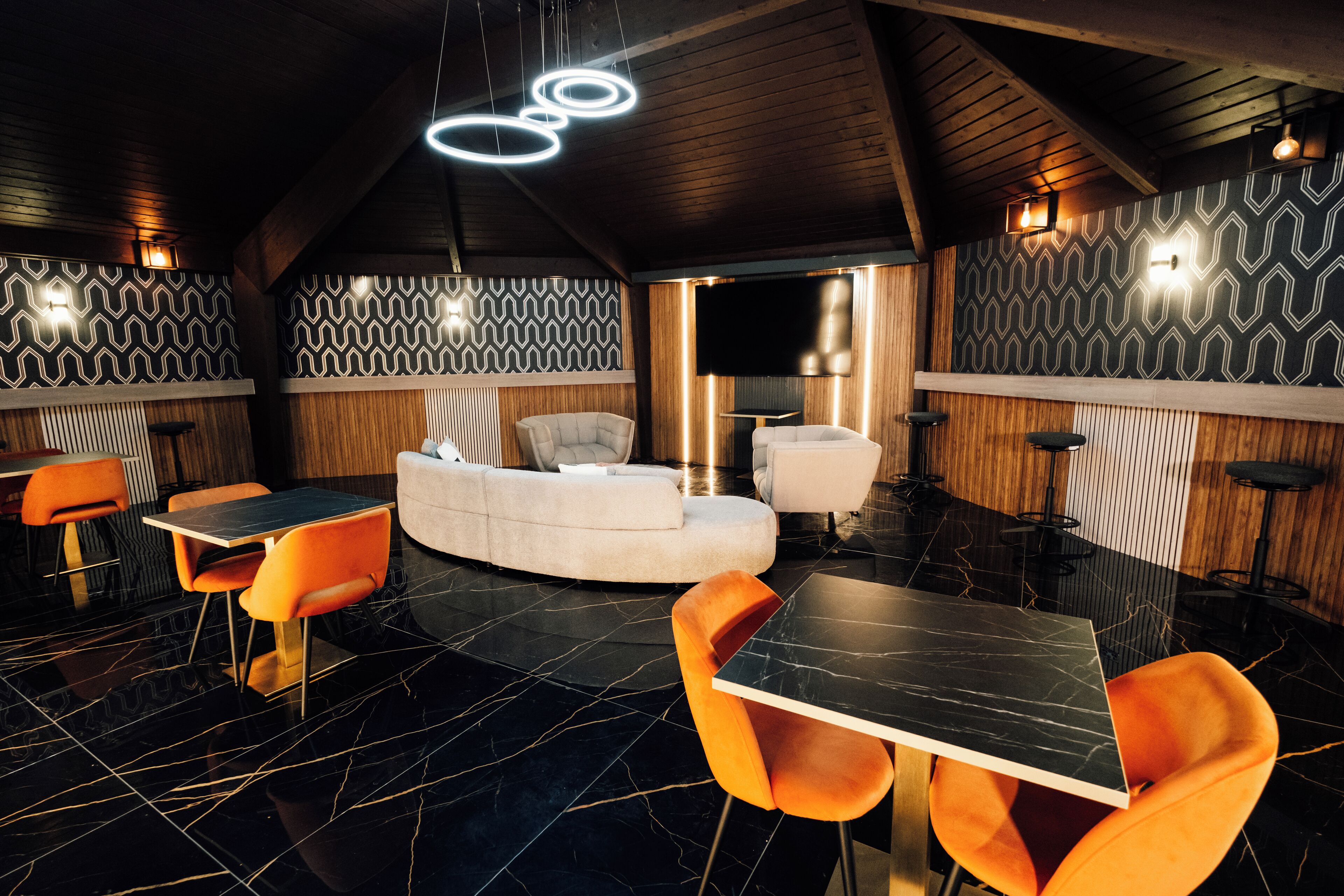 Un intérieur moderne avec un sol en marbre noir, un canapé blanc, des fauteuils orange et une table noire.