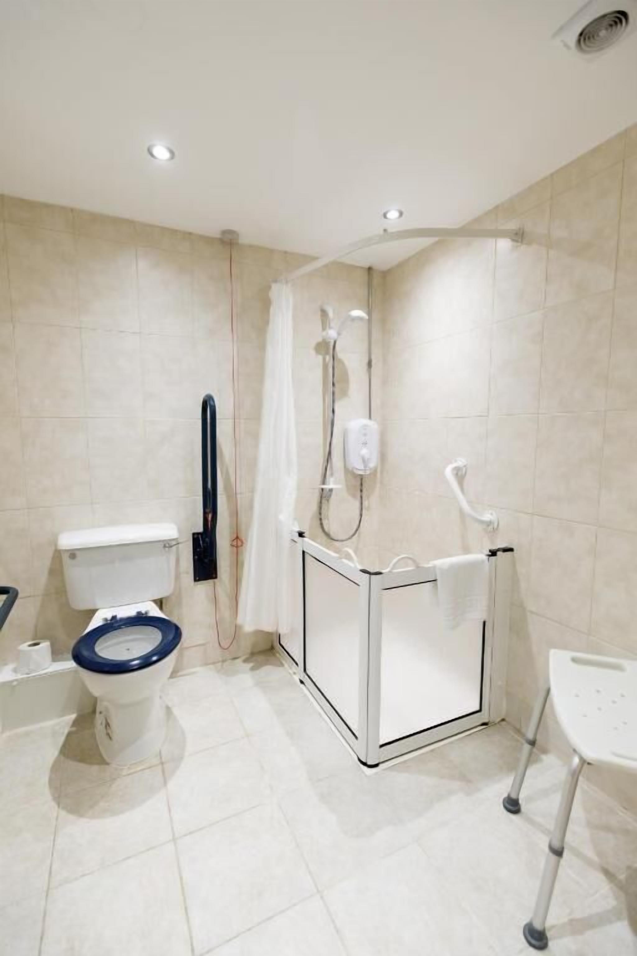 A modern bathroom with a toilet, bidet, shower, and a wheelchair-accessible sink.