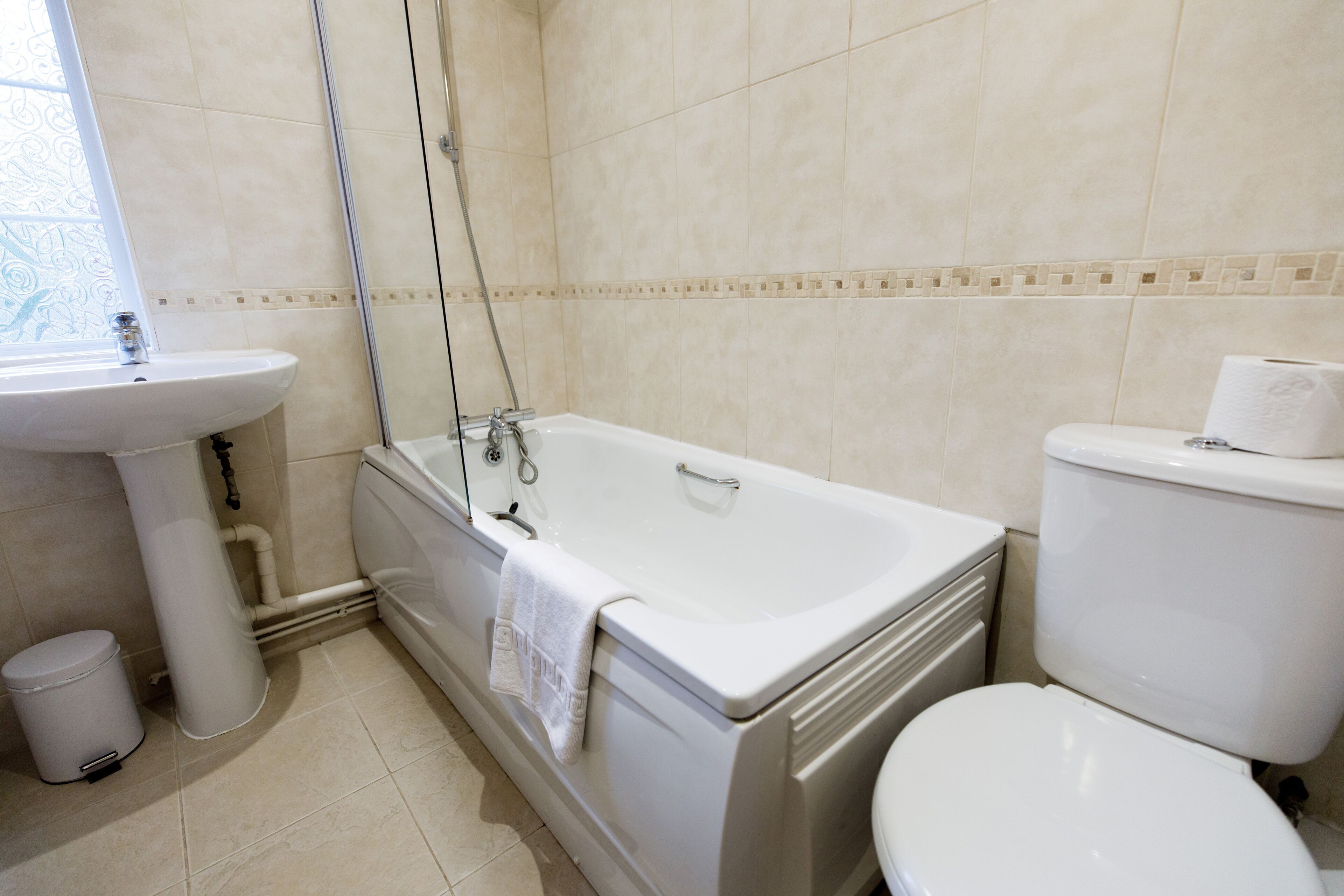 A bathroom with a bathtub, toilet, sink, and a window.