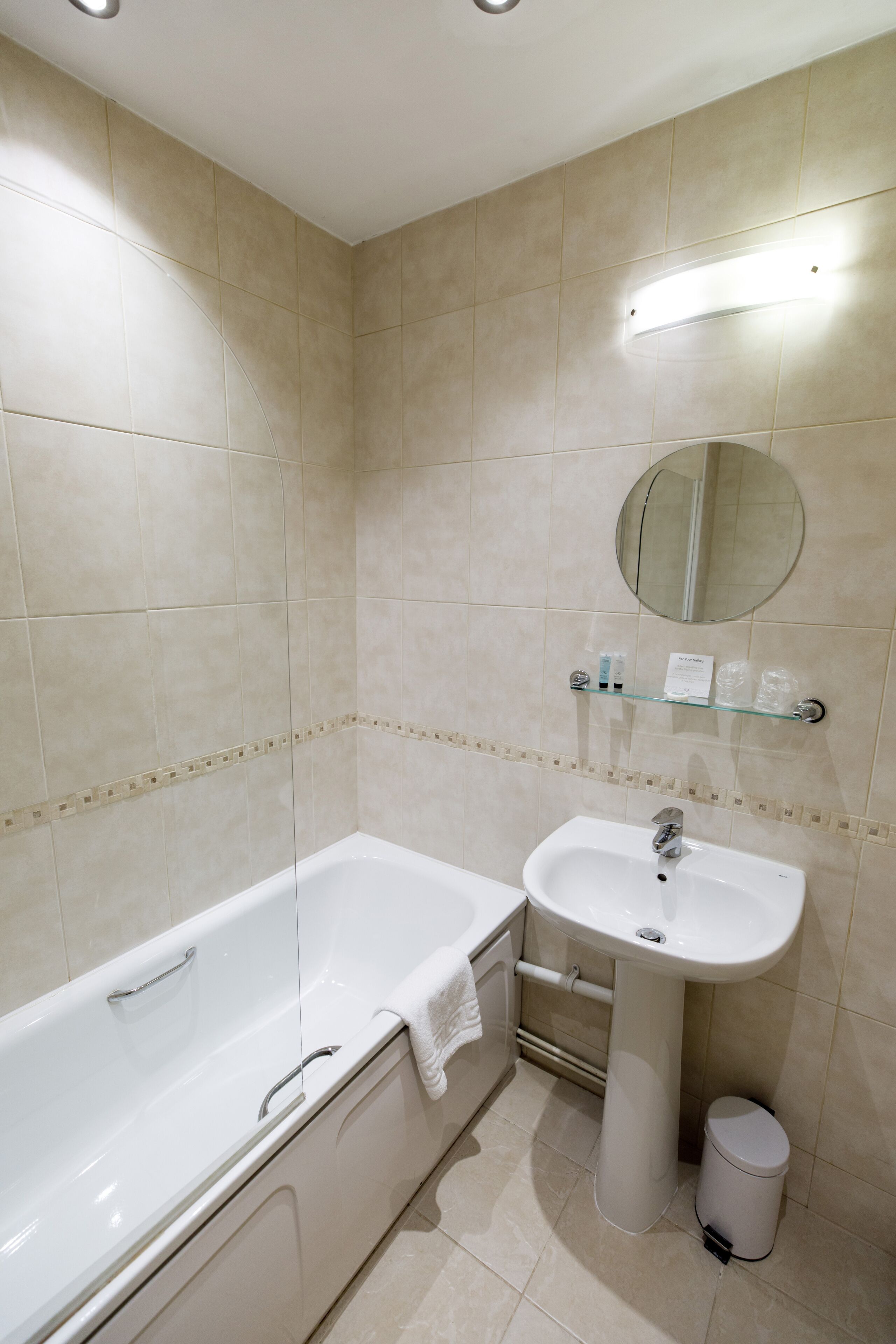 A bathroom with a bathtub, sink, and mirror.