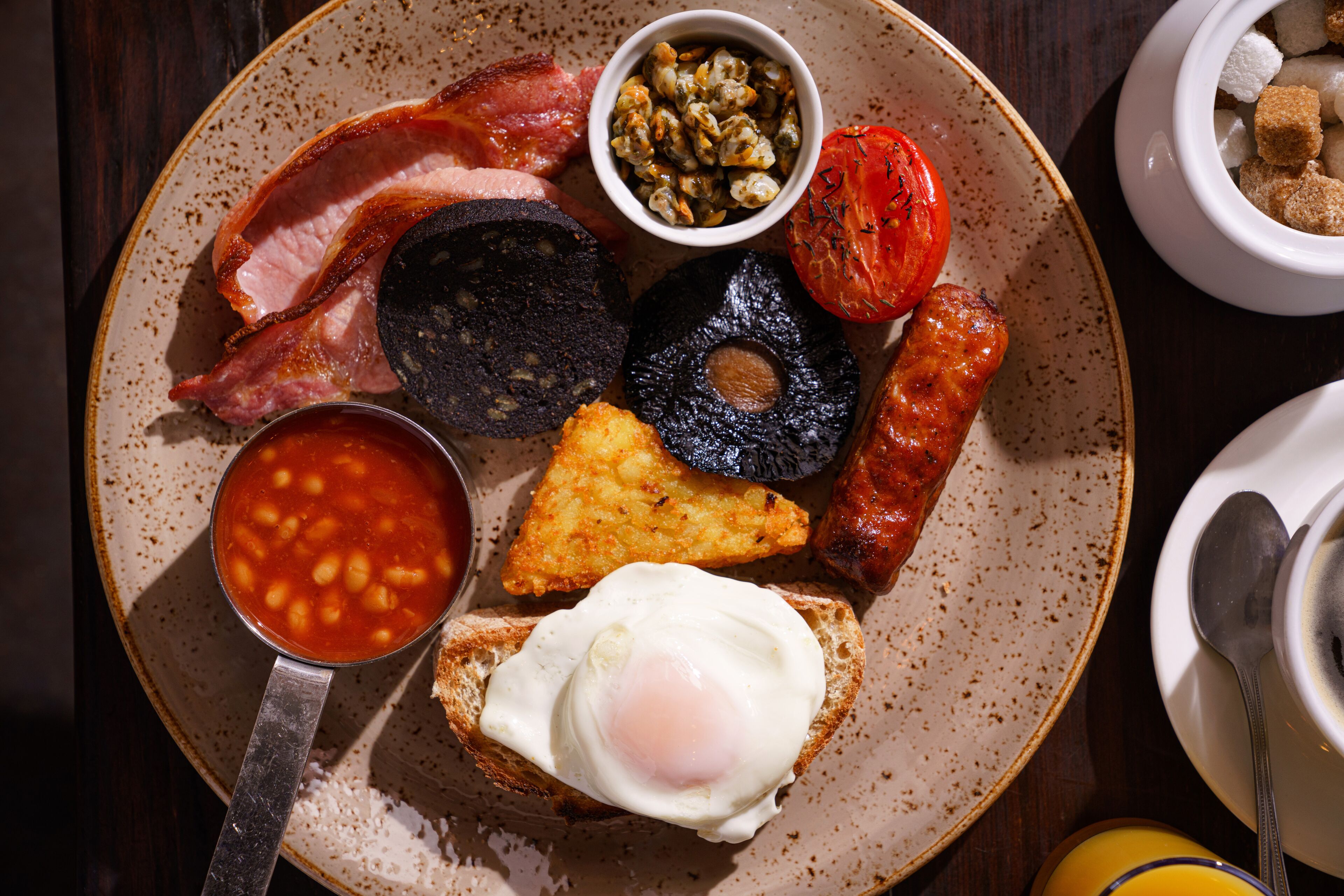 A plate of breakfast food including bacon, sausages, eggs, and toast.