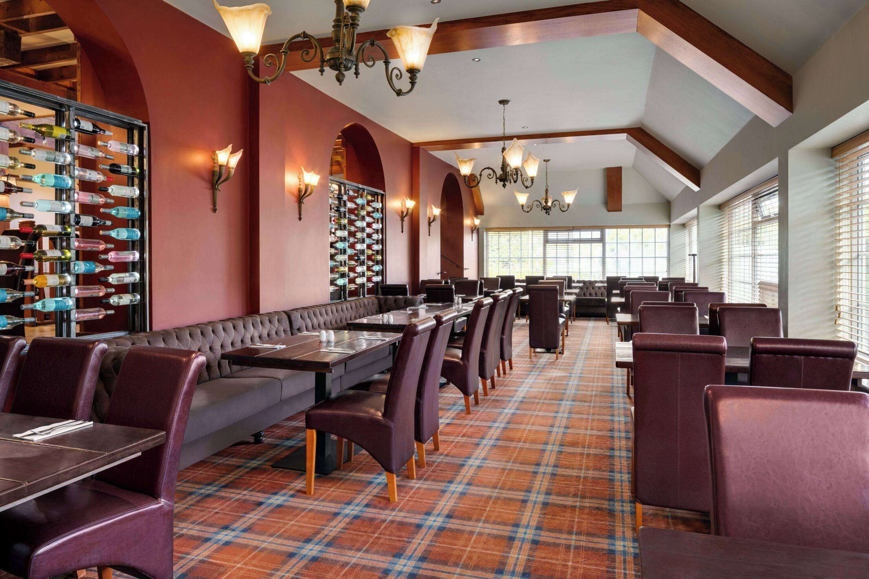 A restaurant with a long counter, multiple tables, and a variety of seating options.