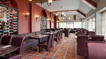 Een restaurant met een lange toonbank, meerdere tafels en diverse zitmogelijkheden.