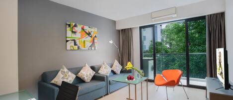 Una habitación moderna con sofá, una mesa de vidrio, una silla y un ventanal grande.