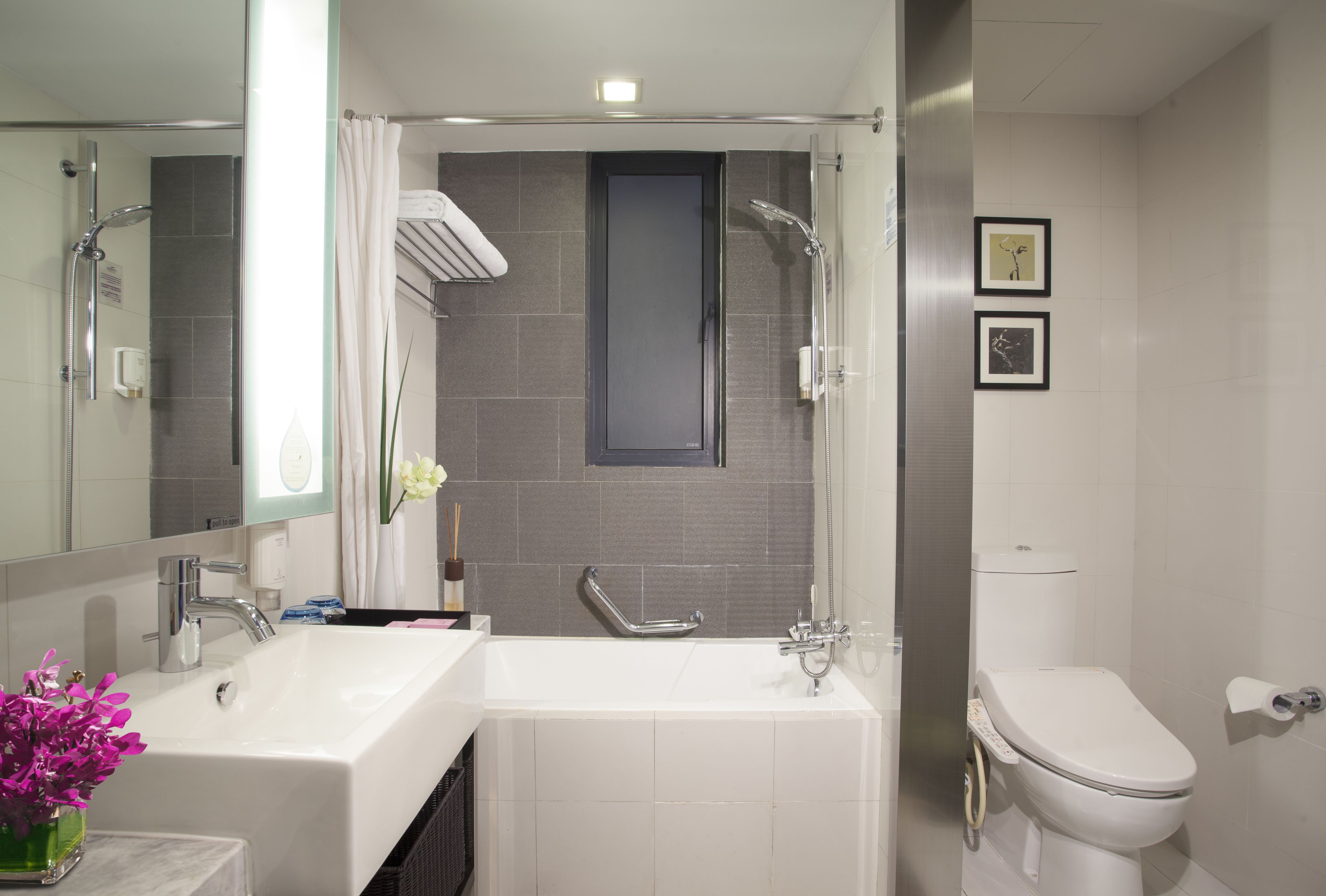 A modern bathroom with a shower, two sinks, a toilet, and a large mirror.