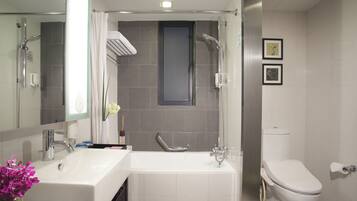 A modern bathroom with a shower, two sinks, a toilet, and a large mirror.