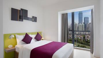 Una moderna camera d'albergo con un letto grande, vista sulla città e un arredamento minimalista.