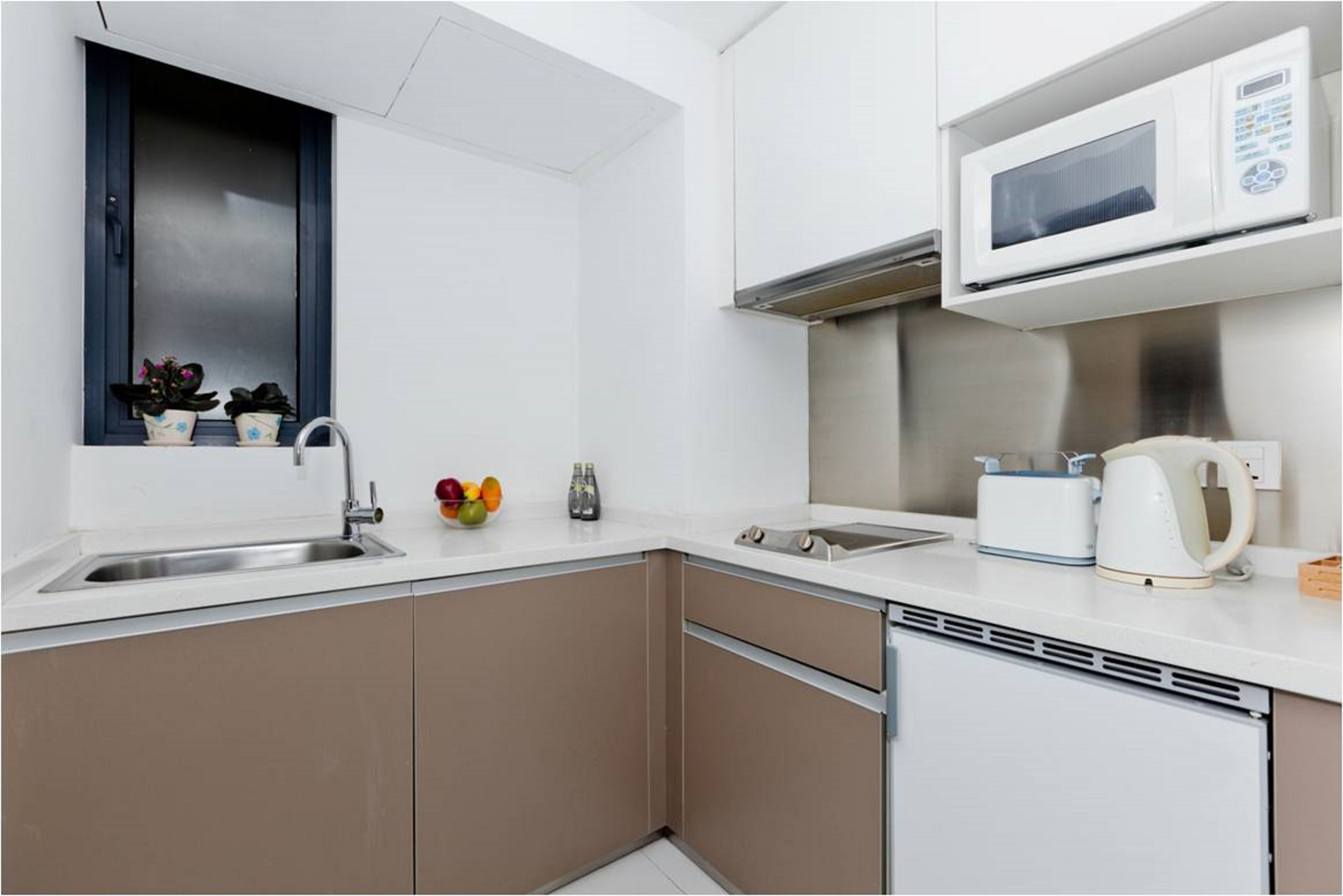 Una cocina moderna con microondas integrado, pileta de acero inoxidable y lavavajillas compacto.