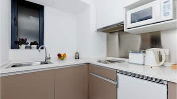 Una cocina moderna con microondas integrado, pileta de acero inoxidable y lavavajillas compacto.