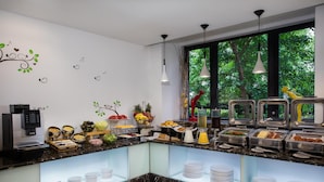 A modern breakfast buffet with a variety of food options, a coffee machine, and a view of greenery through large windows. - Citadines Xinghai Suzhou (Suzhou)
