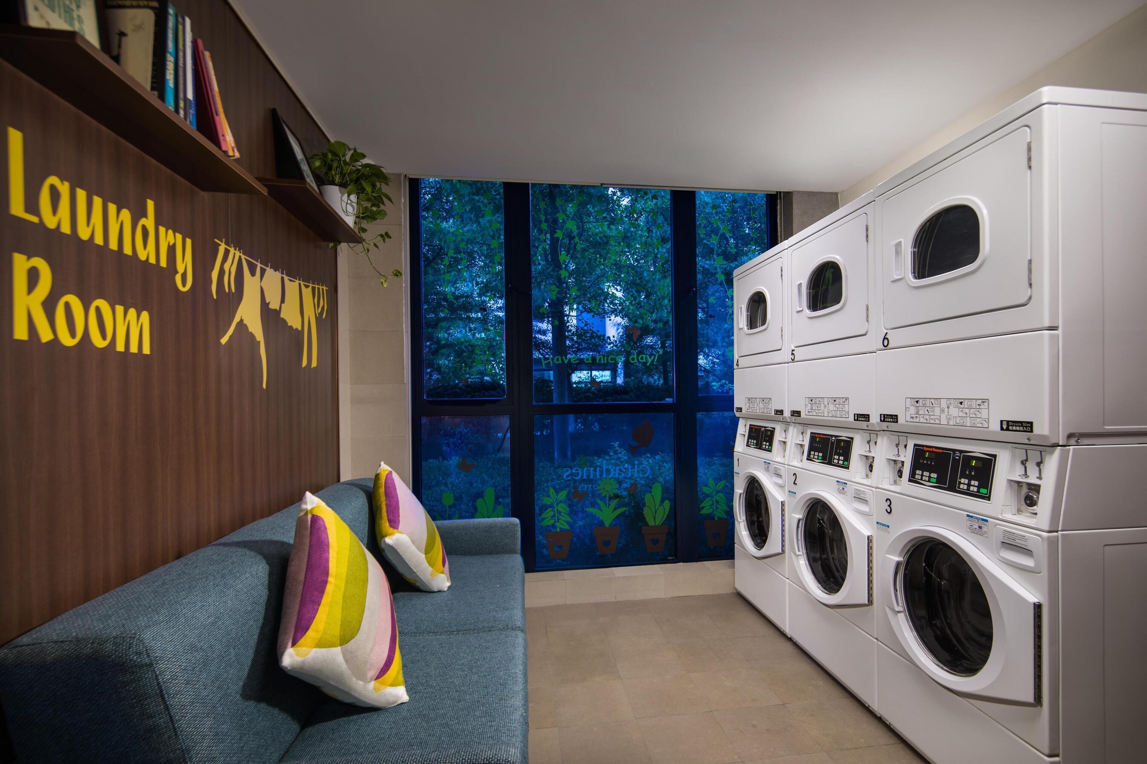Et vaskerum med en blå sofa, farverige puder og et ophængt skilt med teksten "Laundry Room".