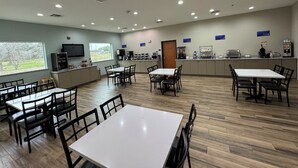 A spacious dining area with multiple tables and chairs, a kitchen counter with appliances, and a television on the wall. - Best Western Cleveland Inn & Suites (Cleveland)