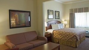 A hotel room with a bed, a sofa, a nightstand, and a painting on the wall. - Best Western Cleveland Inn & Suites (Cleveland)