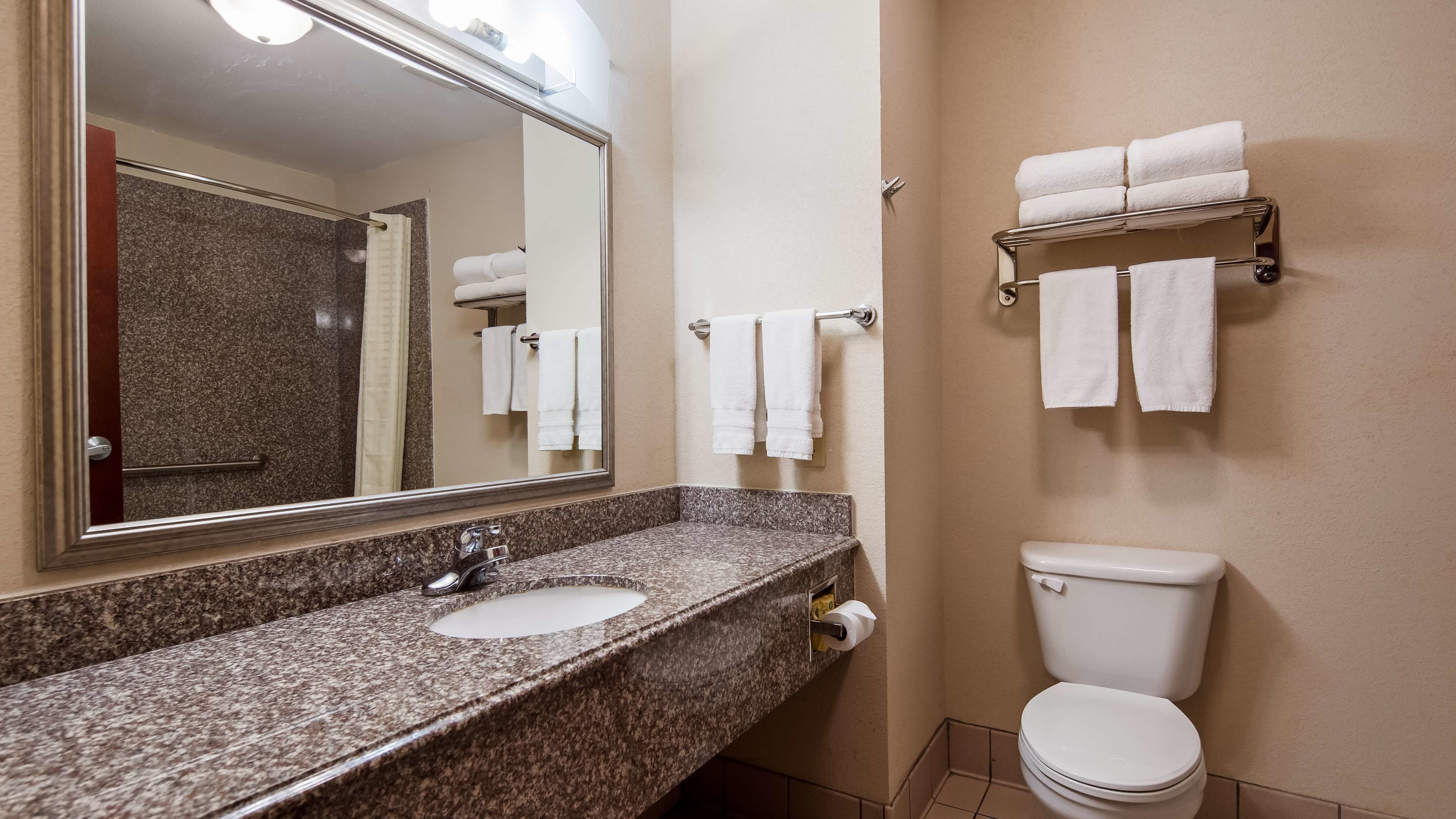 Une salle de bain avec un lavabo en granit, un miroir, des toilettes et des porte-serviettes.