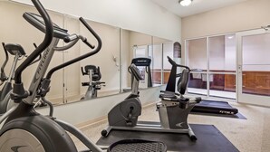 Un gimnasio con diferentes máquinas de ejercicio, un espejo grande y un ventanal.