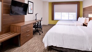 Una camera d'hotel con una scrivania in legno, una televisione a schermo piatto, due letti, un'ampia finestra e una parete color giallo.