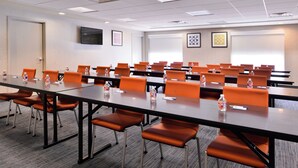 A conference room with multiple tables and chairs, equipped with water bottles and nameplates.