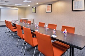 A conference room with a long table, orange chairs, water bottles, and a projector screen. - Holiday Inn Express & Suites Selma by IHG (Selma)
