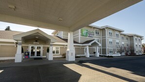 A Holiday Inn Express building with a covered entrance, a sign indicating valet parking, and a clear sky. - Holiday Inn Express Hotel & Suites Iron Mountain by IHG (Iron Mountain)