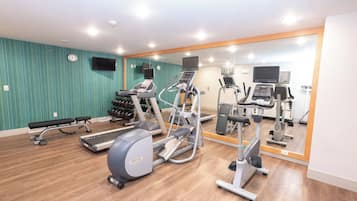 Une salle de sport équipée de tapis de course, de vélos elliptiques et de poids libres.